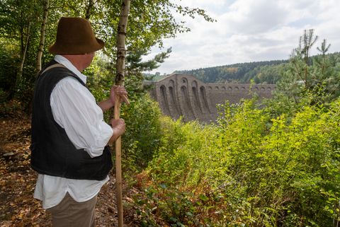 Ein Wanderer schaut auf eine riesige Mauer an der Talsperre Klingenberg. 