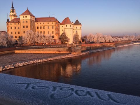 Winterlicher Blick von der Elbbrücke aus auf Schloss Hartenfels in Torgau.