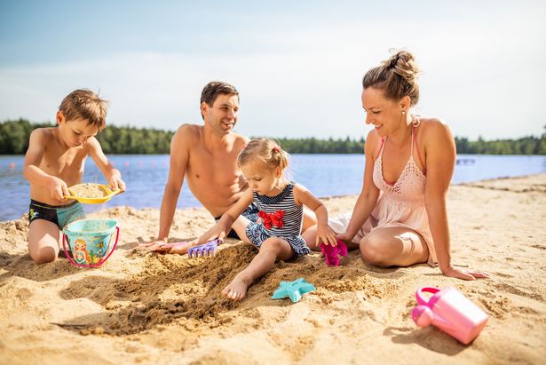 Familie am Strand beim Sandburg bauen