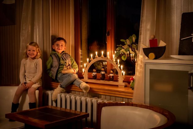 Kinder sitzen am Fenster mit Schwibbogen