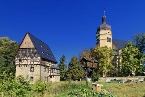 Ein großes Haus und eine gelbe Kirche stehen nebeneinander in Kürbitz. 