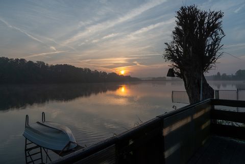 Blick auf die Koberbach Talsperre in Blankenhain. Am Steg liegt ein Boot und die Sonne geht gerade unter.