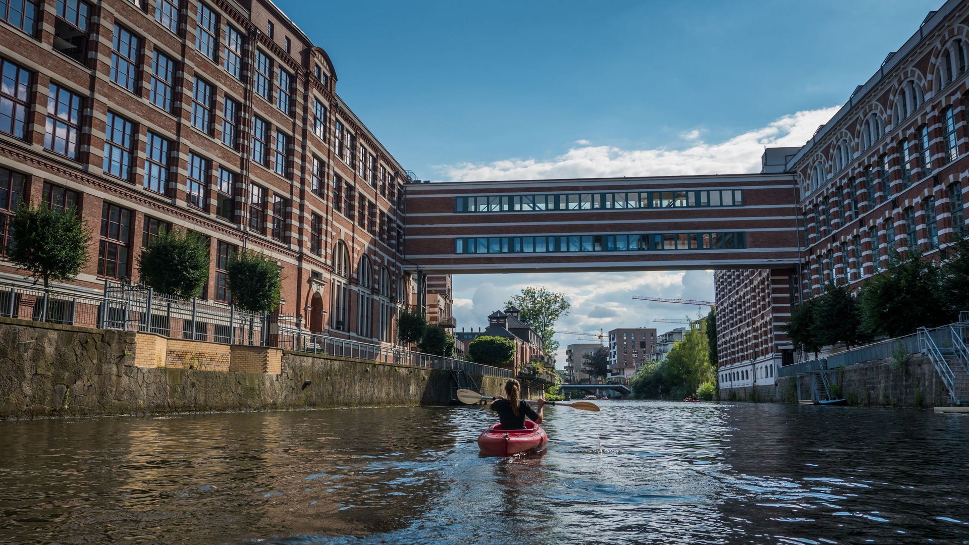 Kajak fährt auf dem Wasser auf Gebäude in attraktiver roten Backsteinarchitektur zu 