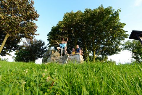 Eine Familie steht an einem Mauerstück auf einer Wiese. Sie sind in Obercunnersdorf. 