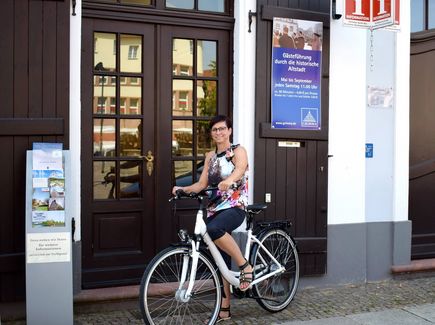 Radfahrerin steht vor dem Eingang der Tourismusinformation