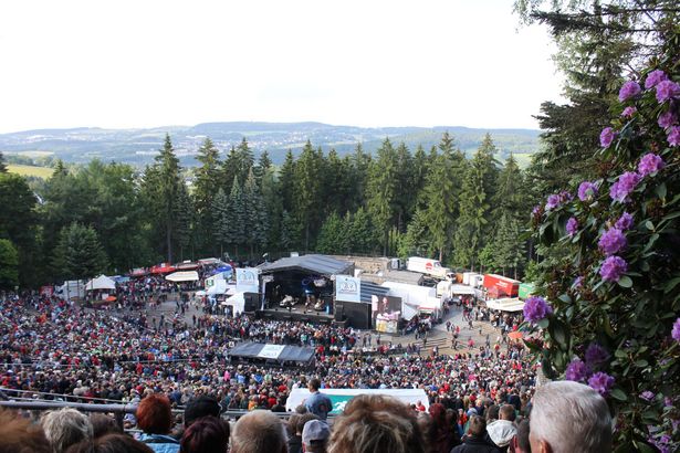 Zuschauer sitzen bei einem Opan-Air Konzert auf der Waldbühne bei Schwarzenberg. 