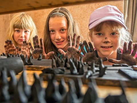Drei Mädchen mit schwarzen Händen betrachten die Räucherkerzen, die sie hergestellt haben.