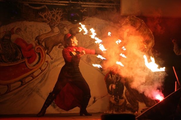 Feuershow auf Festung Königstein. Eine Frau hält Stäbe mit Feuer und tanzt damit. Es ist dunkel und die Flammen sind deutlich zu erkennen.