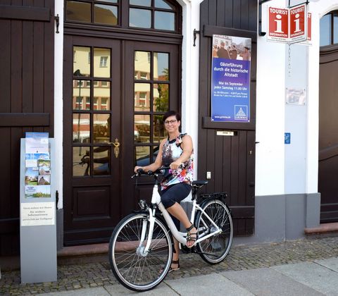 Radfahrerin steht vor dem Eingang der Tourismusinformation