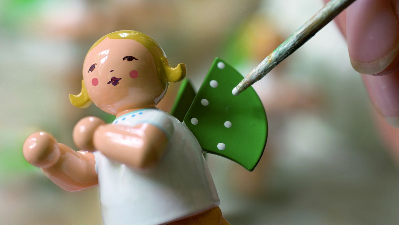 Eine Kunsthandwerkerin setzt den elften Punkt auf einen der Flügel der Elfpunkteengel des Traditionsunternehmens Wendt & Kühn in Großenhain