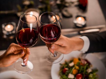 Pärchen stößt mit einem Glas Wein beim Abendessen an.