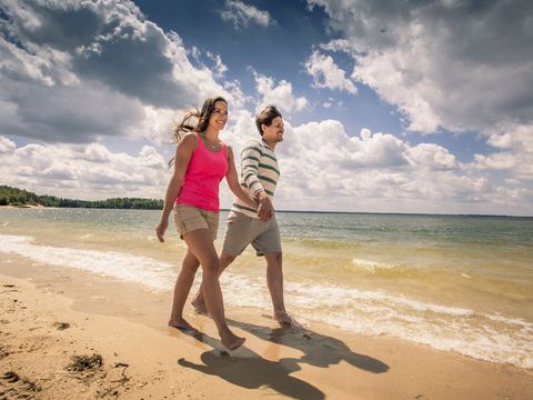 Ein Mann und eine Frau gehen am Strand spazieren. Sie sind am Bärwalder See im Lausitzer Seenland. 