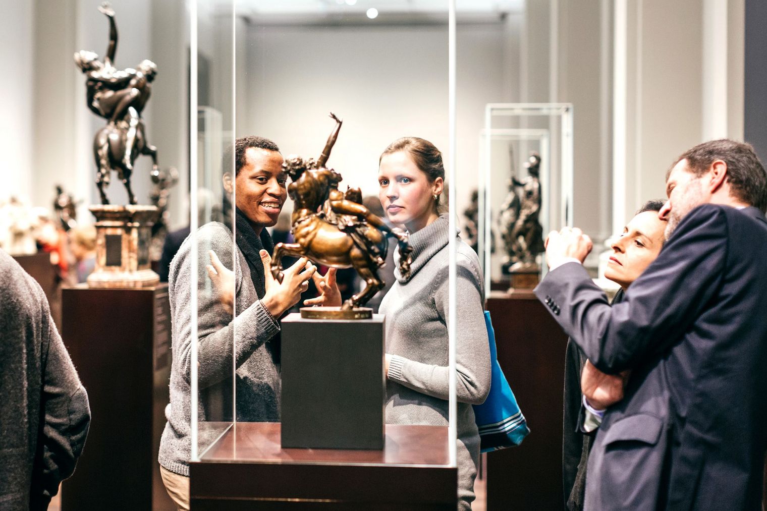 Eine Frau und ein Mann stehen vor einer Vitrine, in der eine bronzene Skulptur steht. 