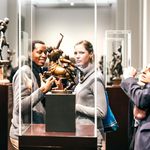 Eine Frau und ein Mann stehen vor einer Vitrine, in der eine bronzene Skulptur steht. 