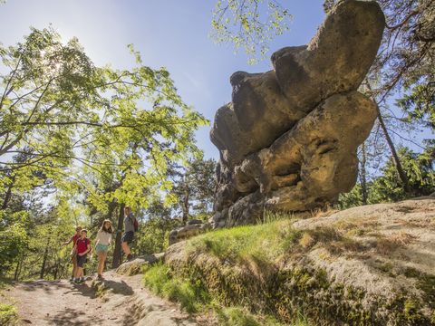 Eine Familie mit zwei Kindern wandert um einen Felsen im Zittauer Gebirge bei Jonsdorf. Sie sind auf dem Oberlausitzer Bergweg.