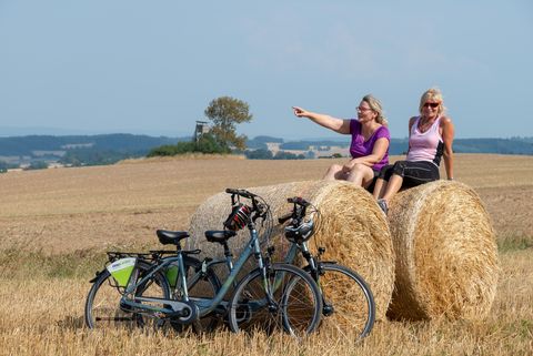 Zwei Frauen sitzen auf Heuballen. Sie sind mit dem Fahrrad bei Kürbitz unterwegs. 