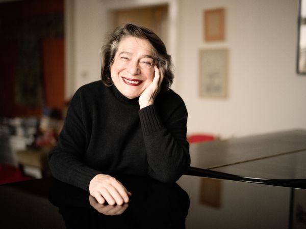 Elisabeth Leonskaja sitzt an einem Tisch und lächelt in die Kamera