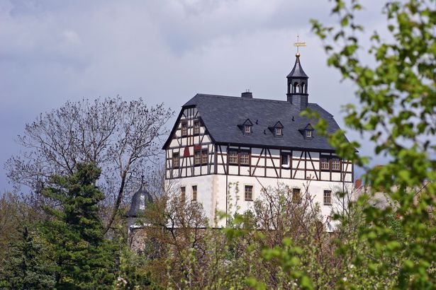 Ein großes Jägerhaus im Stile eines Fachwerkhauses und mit einem kleinen Turm steht in Jössnitz im Vogtland. 