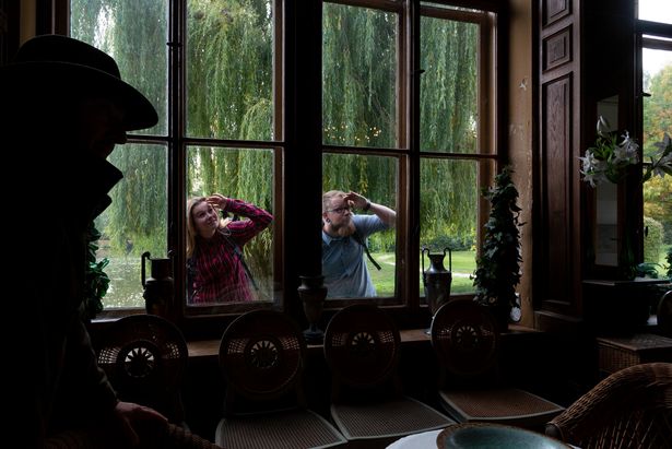 Ein Mann und eine Frau schauen durch ein Fenster. Sie sind am Schloss in Blankenhain. 