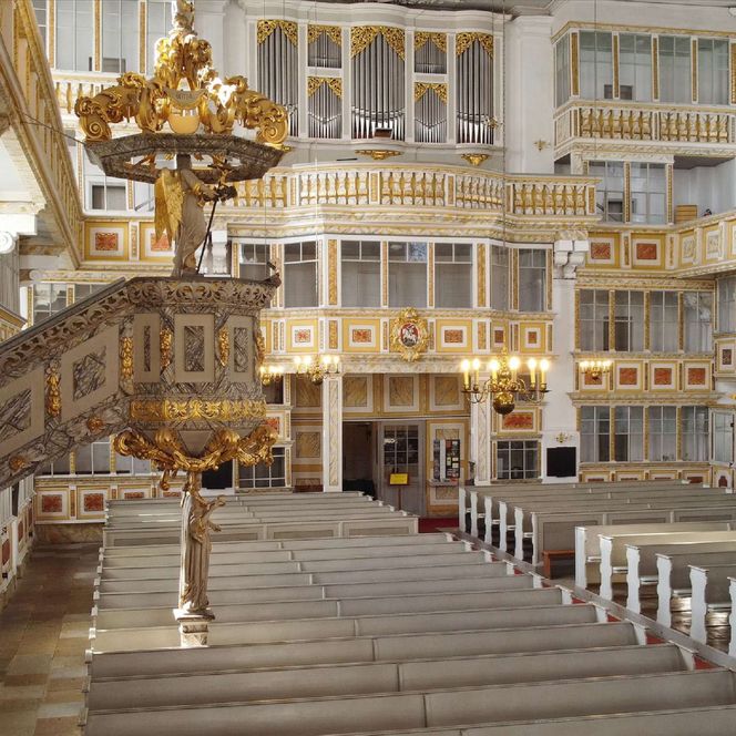 Der Blick ins Kirchenschiff mit den weißen Bänken und goldenen Verzierungen in der Kirche von Schwarzenberg. 
