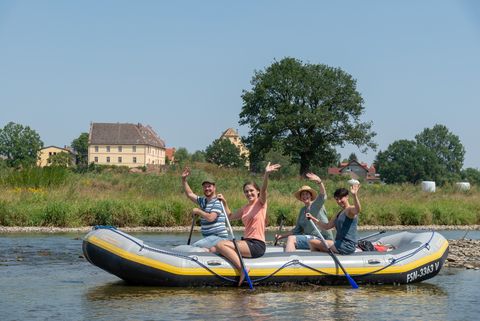 Vier Personen sitzen auf einem Schlauchboot auf der Mulde. Sie fahren in der Region von Kössern. 