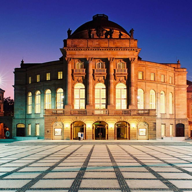 Außenansicht der Oper Chemnitz am Theaterplatz, Gebäudefassade wird beleuchtet, da es dunkel ist