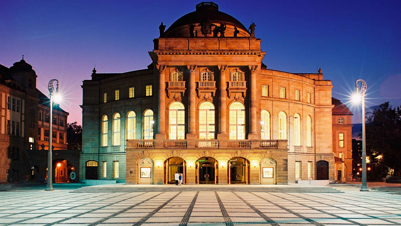 Außenansicht der Oper Chemnitz am Theaterplatz, Gebäudefassade wird beleuchtet, da es dunkel ist