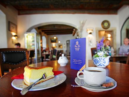 Auf einem Tisch in Ilses Kaffeestube stehen eine Eierschecke und eine Tasse Kaffee. Die Kaffeestube ist im Tom Pauls Theater in Pirna. 