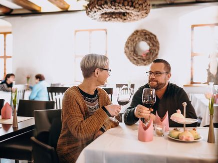 Pärchen sitzt mit einem Glas Wein im Restaurant und stößt an