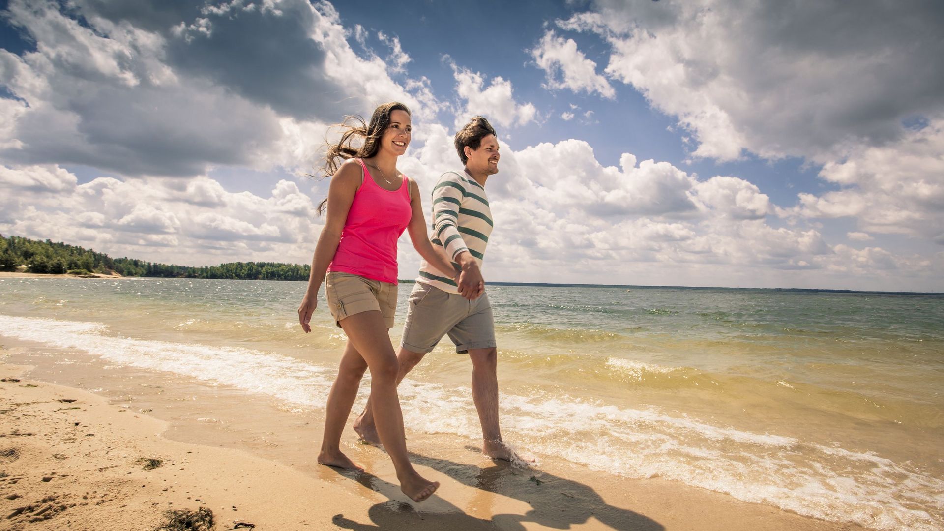 Ein Mann und eine Frau gehen am Strand spazieren. Sie sind am Bärwalder See im Lausitzer Seenland. 